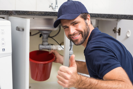 Plumber fixing under the sink in the kitchenの写真素材