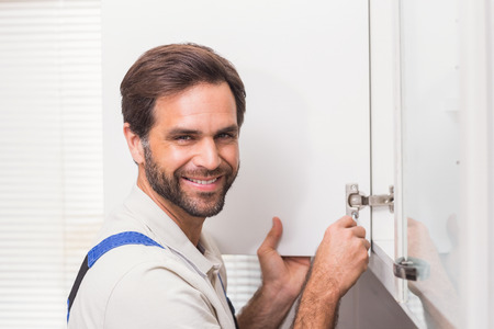 Handyman fixing the cupboard in the kitchenの写真素材
