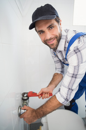 Plumber fixing tap with wrench in the bathroomの写真素材