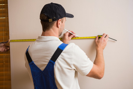 Construction worker using measuring tape in a new house