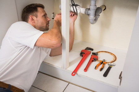 Plumber fixing under the sink in the kitchenの写真素材