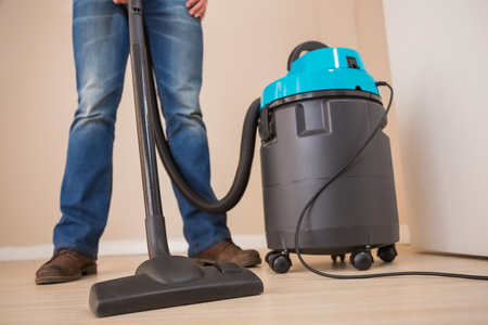 Close up a young man vacuuming at homeの写真素材