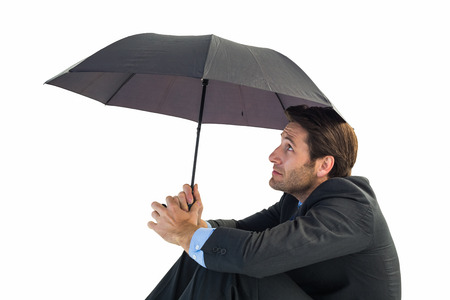 Businessman holding umbrella sitting on the floor on white backgroundの写真素材