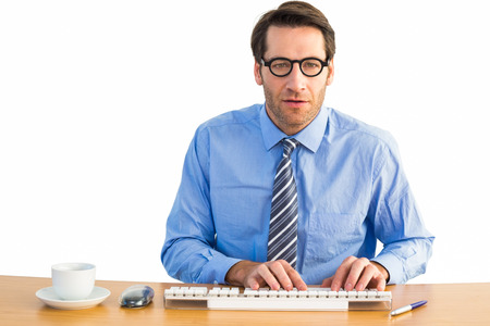 Businessman typing on his keyboard wearing glasses on white backgroundの写真素材