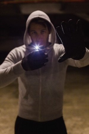 Man in hood jacket standing while making light with his phone on black background