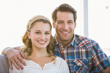 Loving couple looking at the camera in bright living roomの写真素材