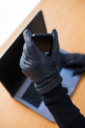 Hands with leather gloves using laptop and smartphone on white backgroundの写真素材