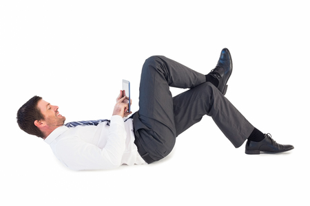 Businessman lying and using tablet on white backgroundの写真素材