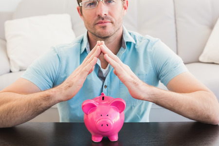 A man with piggy bank at home in the living roomの写真素材