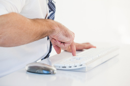 Mid section of businessman using computer keyboard on white backgroundの写真素材
