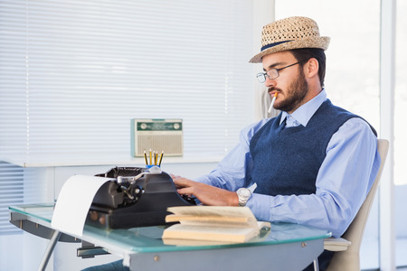 Businessman working on typewriter while smoking in the officeの写真素材