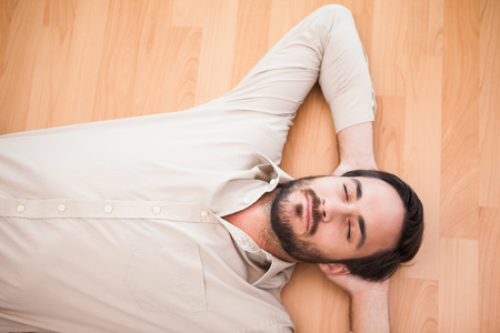 Young man lying on floor thinking in the living roomの写真素材