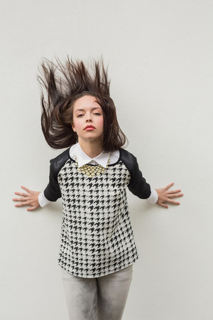 Pretty hipster posing for camera against grey wallの写真素材