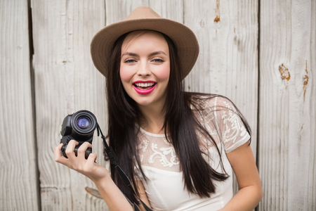 Pretty brunette holding her camera against bleached wooden planksの写真素材
