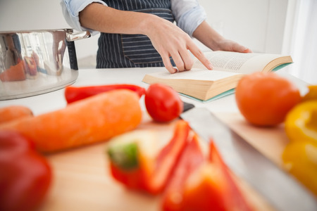Woman following a recipe in book at home in the kitchenの写真素材
