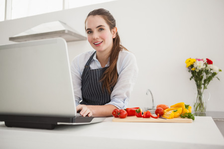 Pretty brunette following online recipe at home in the kitchenの写真素材
