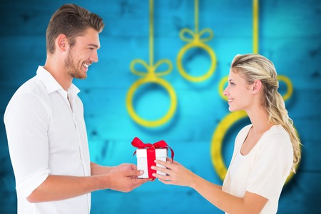 Young couple with gift against blurred christmas background