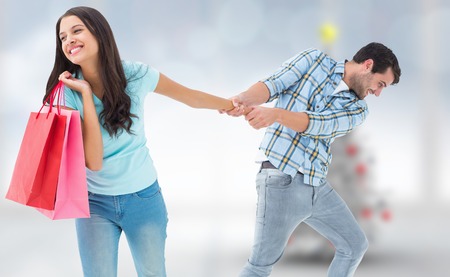Happy couple with shopping bag against blurry christmas tree in roomの写真素材