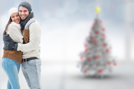 Young winter couple against blurry christmas tree in roomの写真素材