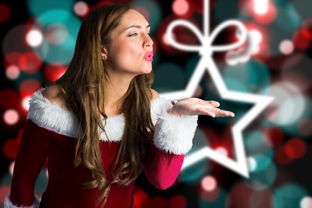Sexy santa girl blowing a kiss against blurred christmas backgroundの写真素材
