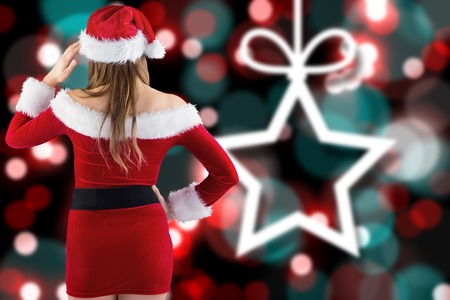 Sexy santa girl with hand on hip against blurred christmas backgroundの写真素材