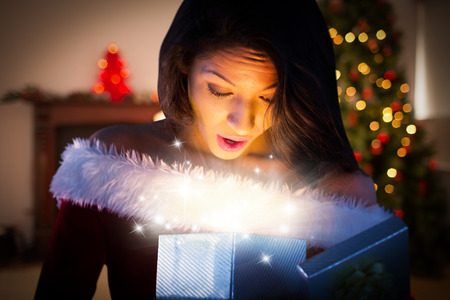 Sexy santa girl opening gift against christmas at homeの写真素材