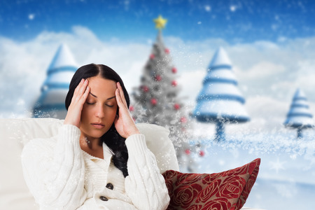 Woman suffering from a migraine against blurry christmas sceneの写真素材