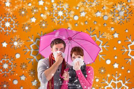 Couple standing underneath an umbrella against snowflake wallpaper patternの写真素材