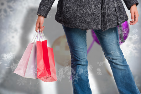 Smiling woman holding shopping bag against blurred christmas decorationsの写真素材