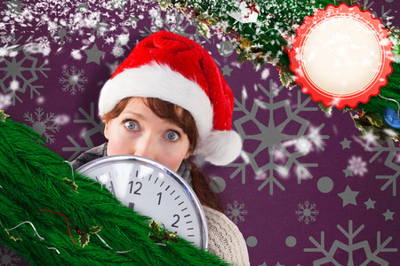Woman holding a large clock against snowflake wallpaper patternの写真素材