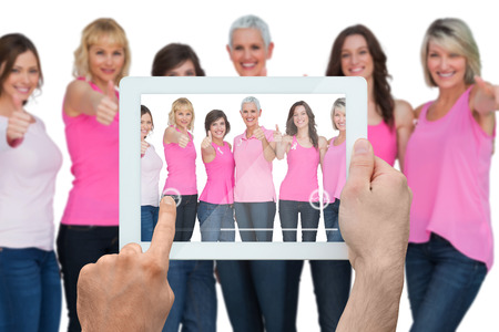 Composite image of hand holding tablet pc showing photograph of breast cancer activistsの写真素材