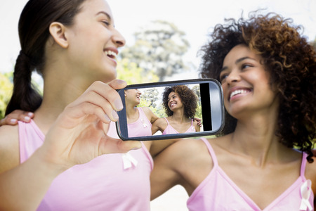 Composite image of hand holding device showing photograph of breast cancer activists
