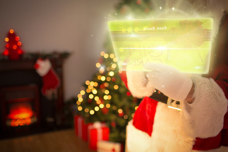 Composite image of santa using futuristic touchscreen at home before christmasの写真素材