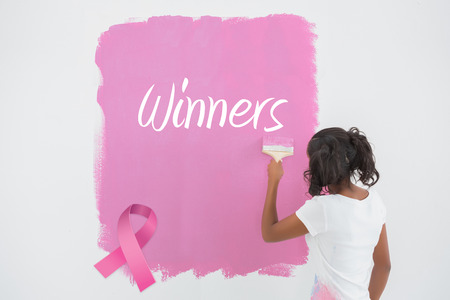 Young woman painting her wall in pink against pink breast cancer awareness ribbonの写真素材