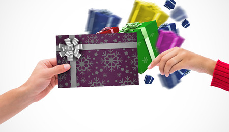 Hands holding card against christmas wrapping paper with bowの写真素材