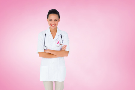 Pretty nurse with arms crossed against pink vignetteの写真素材