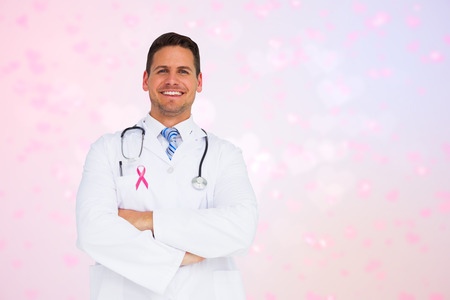 Handsome doctor with arms crossed against pink vignetteの写真素材