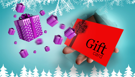 Hand bursting through paper against fir tree forest silhouette over blueの写真素材