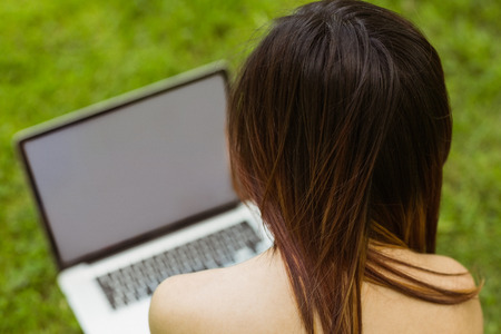Relaxed young woman using laptop in the parkの写真素材