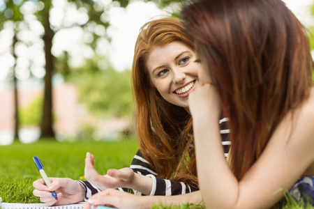Relaxed female college students with books in the parkの写真素材