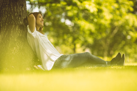 Pretty redhead sitting and smiling in park on a sunny dayの写真素材