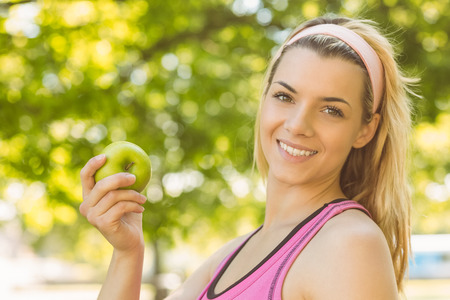 Fit blonde holding green apple on a sunny dayの写真素材