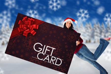 Woman holding a white sign against gift card with festive bowの写真素材