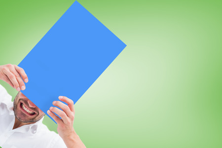 Festive man holding blue card against green vignetteの写真素材