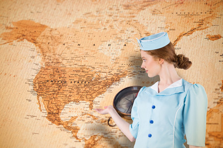 Pretty air hostess presenting with hand against world map with compass showing north americaの写真素材