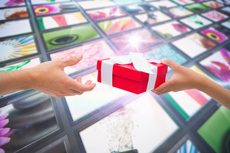 Couple passing a wrapped gift against screen collage showing lifestyle imagesの写真素材