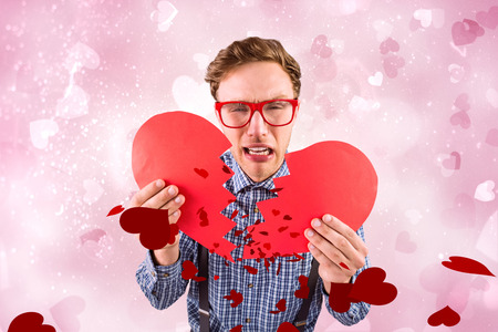 Geeky hipster holding a broken heart  against valentines heart designの写真素材