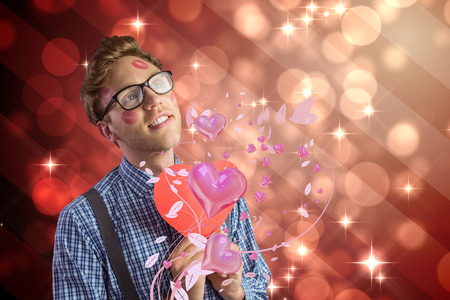 Geeky hipster covered in kisses against light design shimmering on redの写真素材