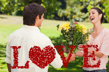 Man presents his friend with flowers against love spelled out in petalsの写真素材