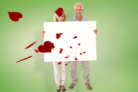 Happy couple holding large poster against green vignetteの写真素材